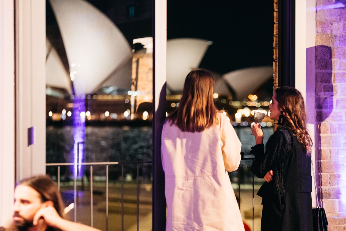 Guests at a Watersedge function looking across the harbour to the lit Sydney Opera House